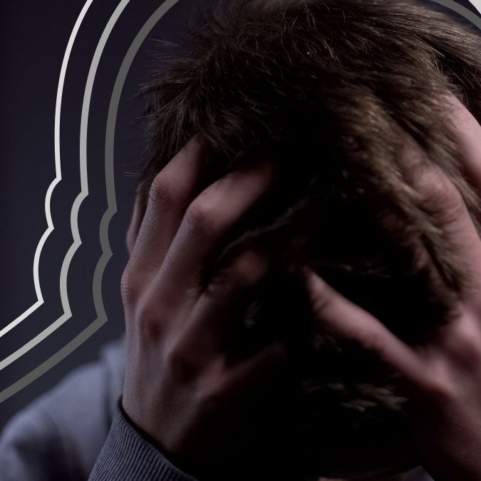 man met hoofd in handen, voor donkere achtergrond